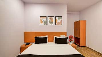 Une chambre d’hôtel comprenant un lit, des tables de chevet, une armoire et trois œuvres d’art encadrées accrochées au mur.