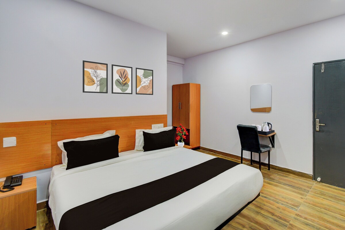 Una habitación de hotel con cama, escritorio con silla, armario y tres cuadros en la pared.