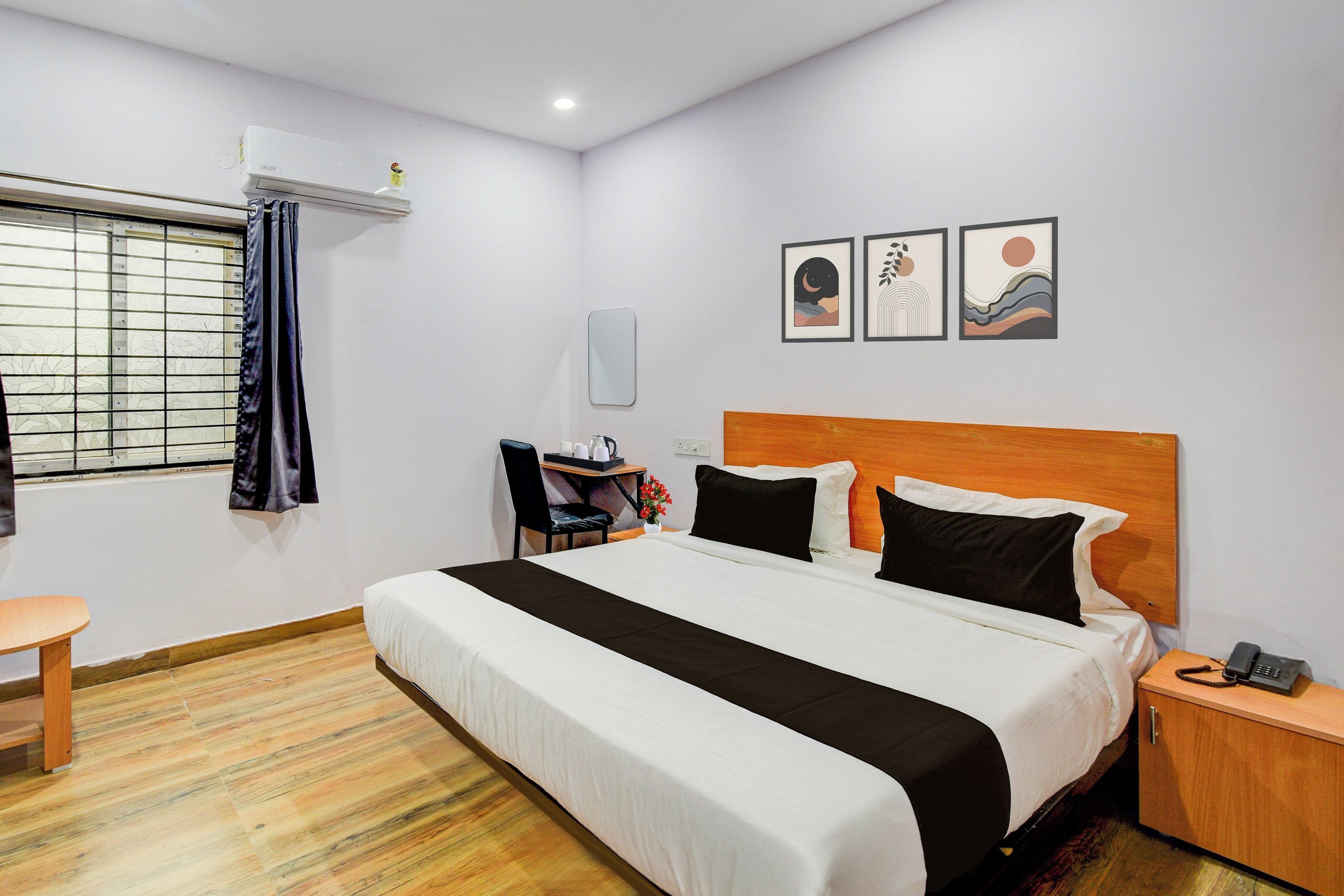 Une chambre d’hôtel comprenant un lit, un bureau, une chaise, une petite table, une table de chevet et un miroir fixé au mur.