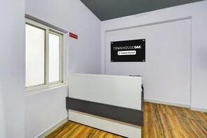 Quarto com cama, placa de recepção e indicação de serviço da empresa.