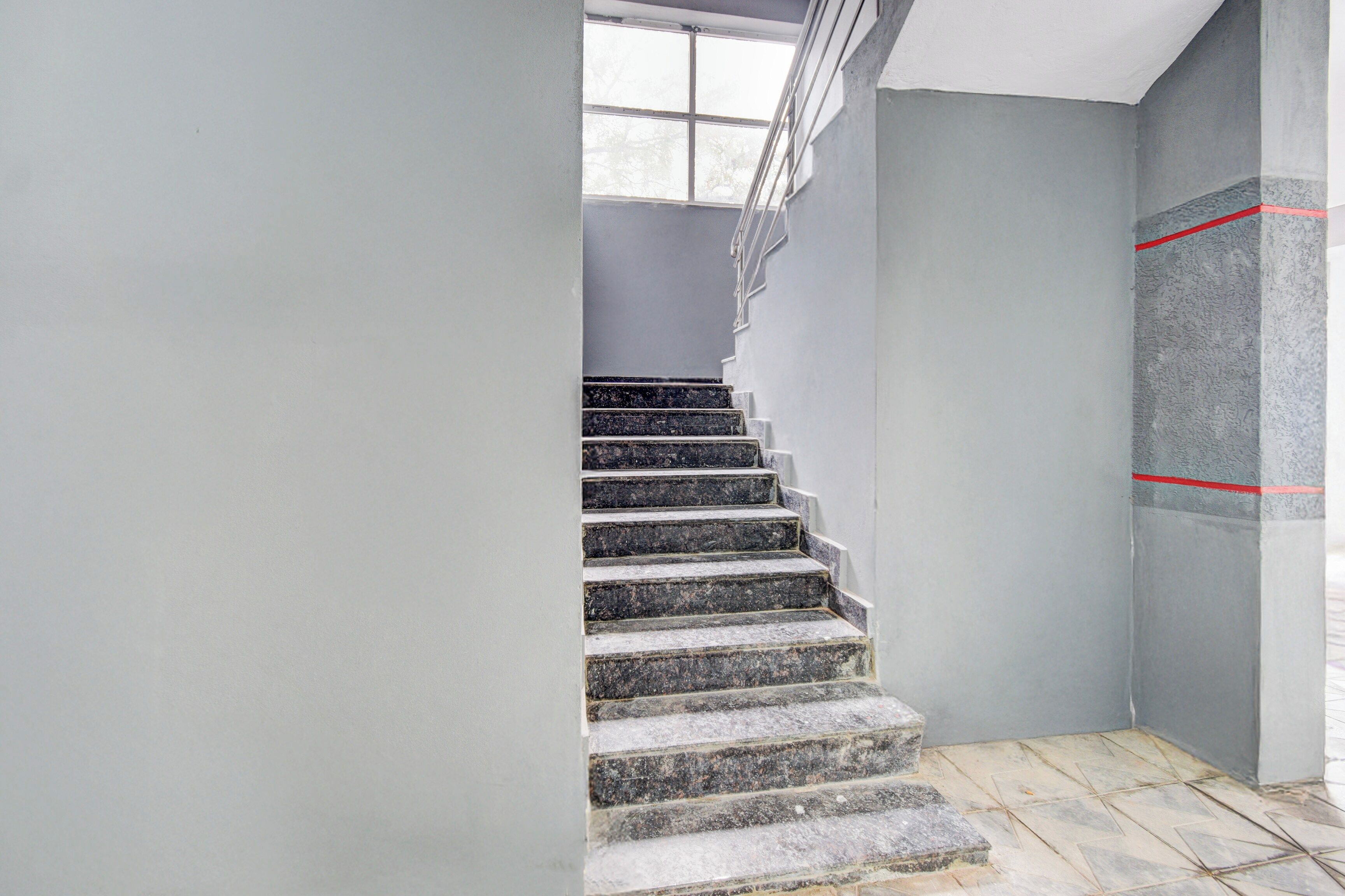 Un escalier avec une rampe, menant à un palier doté d’une fenêtre.