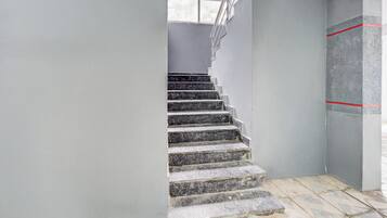 Un escalier avec une rampe, menant à un palier doté d’une fenêtre.