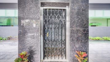 Une entrée moderne, avec un portail en métal, des plantes en pot et un sol carrelé.