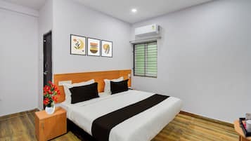 Une chambre d’hôtel avec un lit, une table de chevet, un vase de fleurs et une fenêtre avec des stores.
