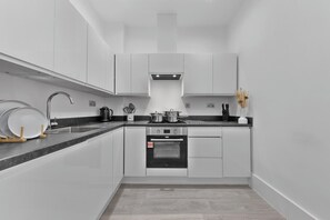 A modern kitchen with white cabinetry, a stainless steel sink, and a built-in oven.