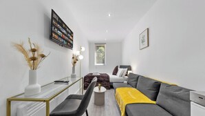 Un salon moderne avec un canapé, une table basse et un téléviseur fixé au mur.