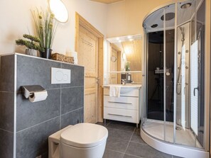 A modern bathroom with a toilet, a shower enclosure, and a vanity with a mirror. - One-bedroom Cabin (Sankt Georgen am Kreischberg)