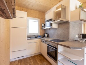 A modern kitchen with wooden cabinets, a built-in oven, a coffee maker, and a window. - One-bedroom Cabin (Sankt Georgen am Kreischberg)