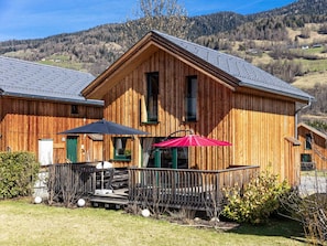 A wooden cabin with a balcony, a table, and two umbrellas. - One-bedroom Cabin (Sankt Georgen am Kreischberg)