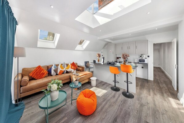 A modern living space with a sofa, ottoman, and bar stools.