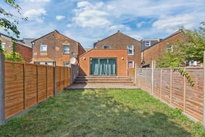 A residential property with a brick house, a wooden fence, and a grassy yard.