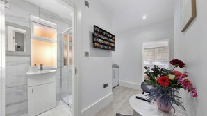 Un baño moderno con cabina de ducha de vidrio, lavamanos blanco y salpicadero de mármol.