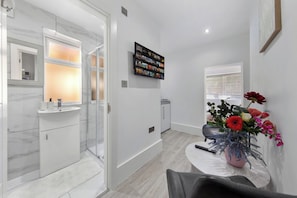 A modern bathroom with a glass shower enclosure, a white sink, and a marble backsplash.