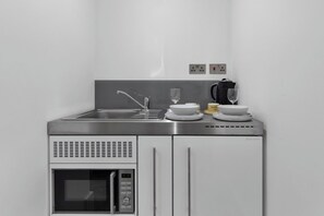 A compact kitchenette with a stainless steel sink, a microwave, and a coffee maker.