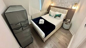 Un dormitorio con cama, mesita de noche, lámpara y ventana.