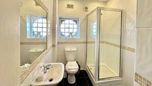 Baño con lavamanos, inodoro y ducha envuelta en vidrio.