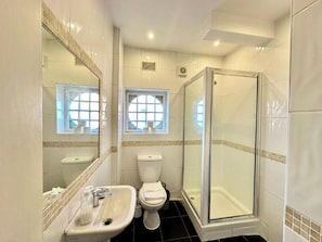 Et badeværelse med vask, toilet og bruseniche.