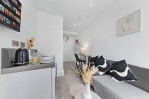 Un espacio de estar moderno con cocina, una mesa de comedor con sillas y un sofá con cojines decorativos.