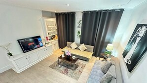 Una sala de estar moderna con una televisión de pantalla plana, un sofá, una mesa de centro y una estantería.