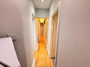 A narrow hallway with wooden flooring and light-colored walls. - Central London Apartment (Greater London)