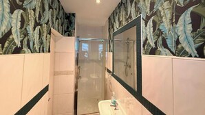 Un baño con ducha, lavabo y espejo.