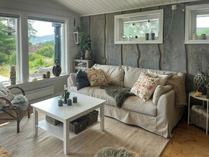 Ein gemütliches Wohnzimmer mit einer Couch, einem Couchtisch und Blick ins Grüne.