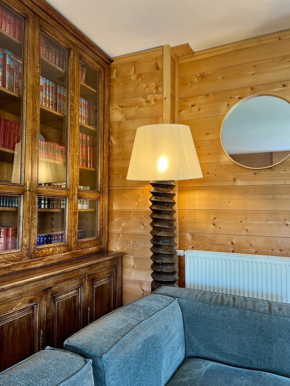 A room with a wooden wall, a bookshelf, a lamp, and a radiator.