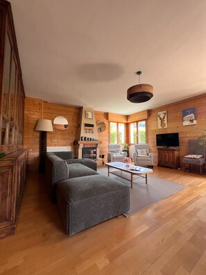 A spacious living room with a fireplace, comfortable seating, and a television.