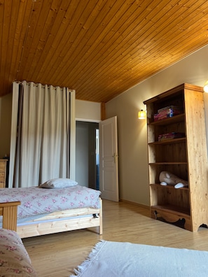 Un dormitorio con techo de madera, una cama con ropa de cama floral, un armario y una mesita de noche.