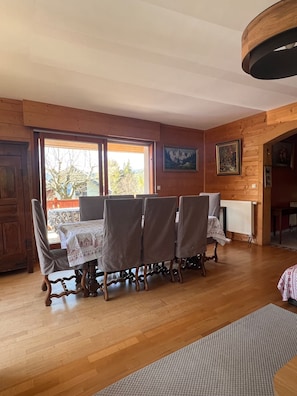 A dining area with a table set for four, wooden walls, and a view through the window.