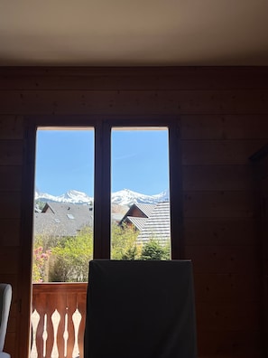 Ein Zimmer mit Holzvertäfelung und Blick auf schneebedeckte Berge durch große Fenster.