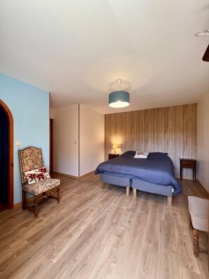 A bedroom with a bed, a chair, a nightstand, and a hanging light fixture.