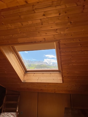 Una habitación con tragaluz, techo de madera y vistas a las montañas.