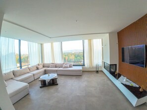 Una sala de estar moderna con un sofá modular, una mesa de centro y un televisor de pantalla plana montado en un panel de madera.