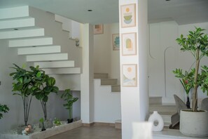 Un interior moderno con una escalera, plantas en macetas y obras de arte en la pared.