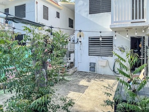 A courtyard with a metal staircase, potted plants, and a building with multiple windows and air conditioning units.