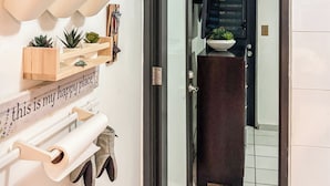 Un pasillo con una puerta que da a una habitación, un estante fijado a la pared con varios objetos, y un letrero que dice 'this is my happy place'.