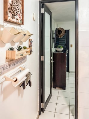 A hallway with a door leading to a room, a wall-mounted shelf with various items, and a sign that reads 'this is my happy place.'