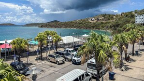 A coastal parking area with vehicles, palm trees, and a view of the sea and hills. - Turtle Nest (Culebra)