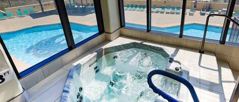 A hot tub with a view of a beach and pool area.