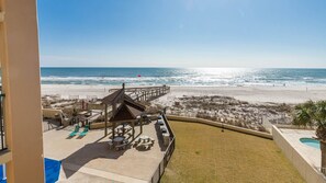 A beachside view with a pool, lounge chairs, and a gazebo. - Phoenix I 1021 3 Bedroom Condo (Orange Beach)