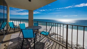 A balcony with a view of the beach, a table, and chairs. - Phoenix I 1098 3 Bedroom Condo (Orange Beach)