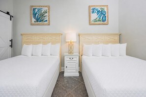 A hotel room with two beds, a nightstand with a lamp, and two wall-mounted paintings. - Phoenix I 1152 3 Bedroom Condo (Orange Beach)