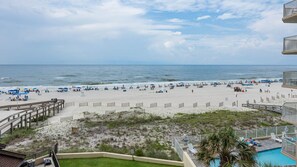 A beach view from a balcony with a pool, beach umbrellas, and a wooden boardwalk. - Phoenix I 1031 3 Bedroom Condo (Orange Beach)