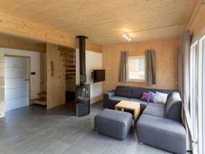 A modern interior with a fireplace, a sofa, a small table, and a staircase leading to another room. - One-bedroom Cabin (Sankt Georgen am Kreischberg)