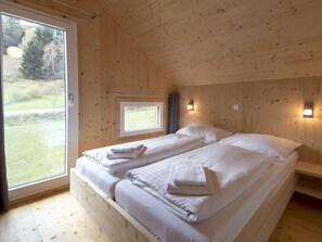 A wooden room with a bed, a window, and a wall-mounted light fixture. - One-bedroom Cabin (Sankt Georgen am Kreischberg)
