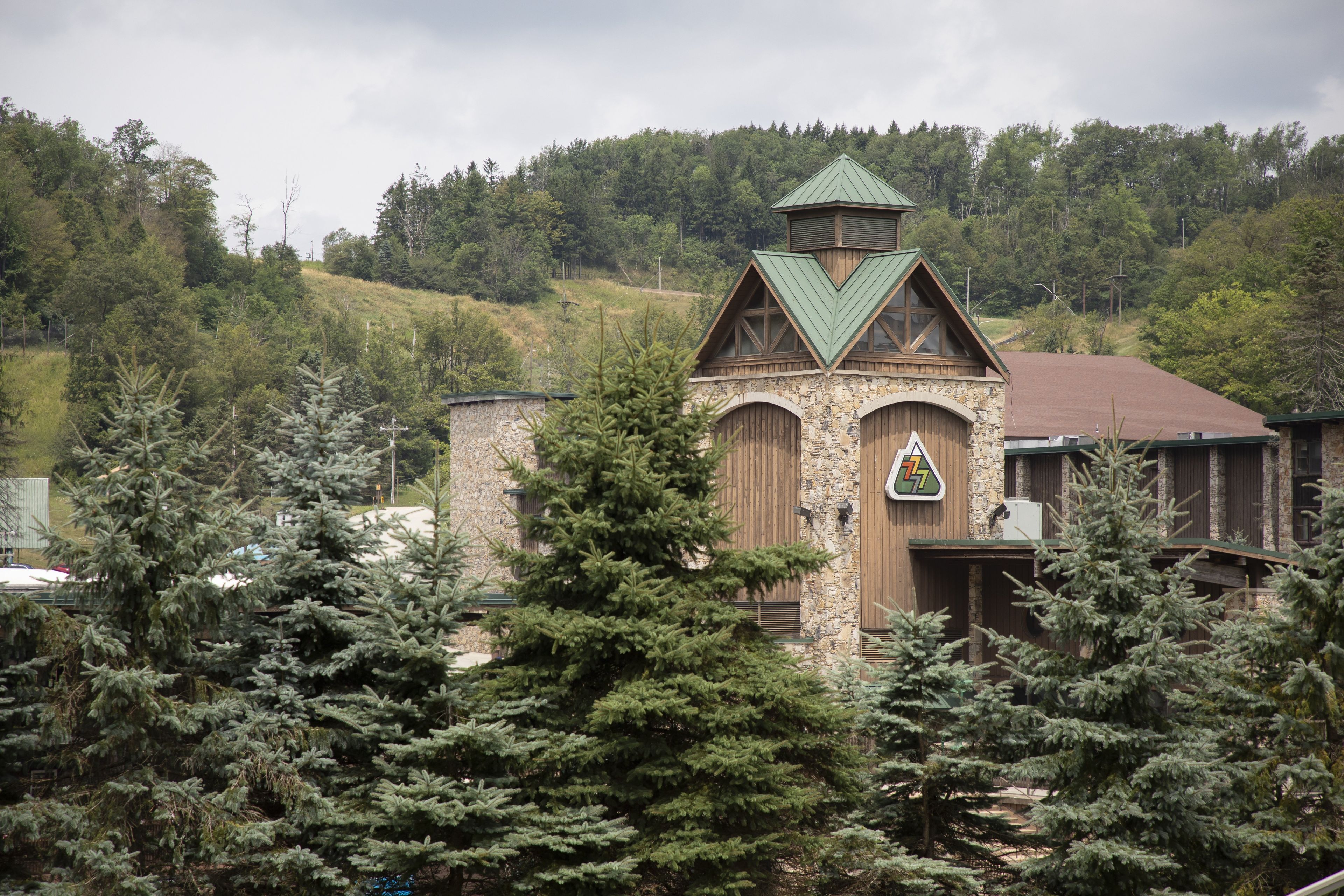 Eine Lodge mit einer Steinaußenwand, einem begrünten Dach und einem Glockenturm.