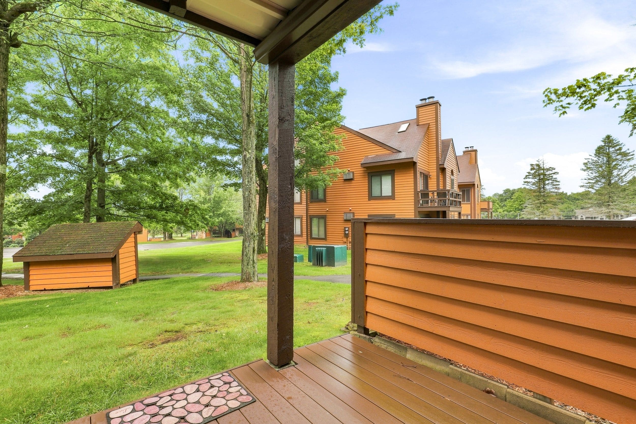 Ein Holzhaus mit einer Laube, einem eingezäunten Garten und einem kleinen Geräteschuppen.