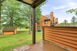 Una casa de madera con un porche cubierto, un patio cercado y un pequeño cobertizo.