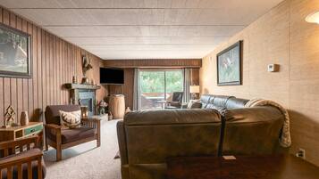 A cozy living room with a leather sofa, wooden furniture, a fireplace, and a television.